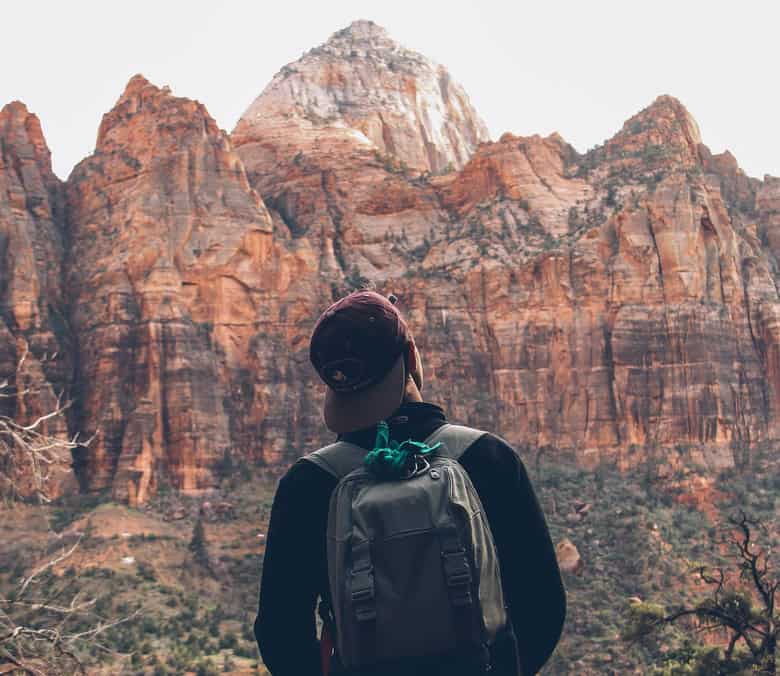 Hiker admiring majestic mountain range with rugged cliffs and peaks.