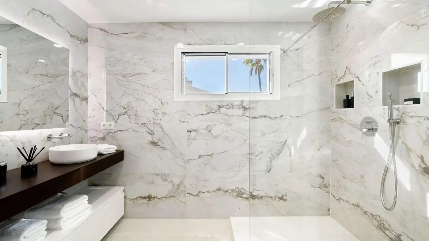 Modern marble bathroom with walk-in shower and ocean view window for luxury living.