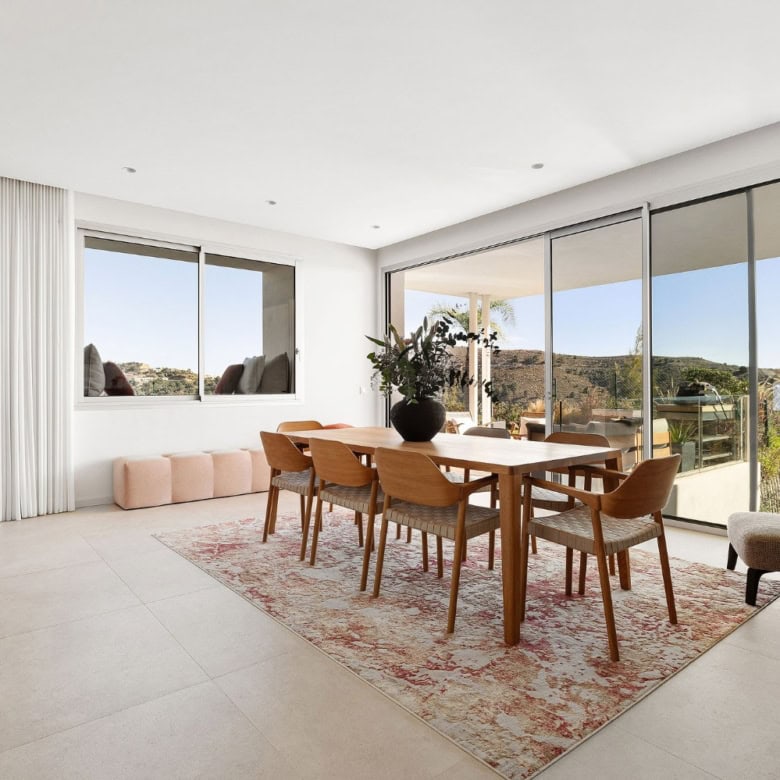 Bright living room with large windows showcasing sea and mountain scenery in Marbella.