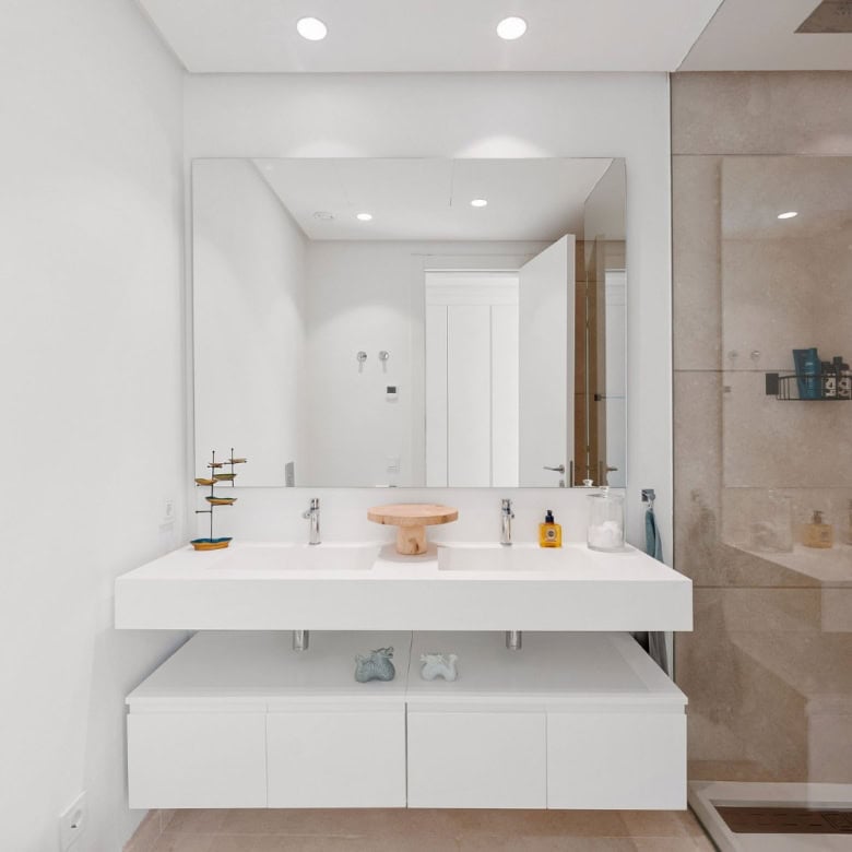 Modern bathroom with white vanity and glass shower in Marbella apartment with sea and mountain views.