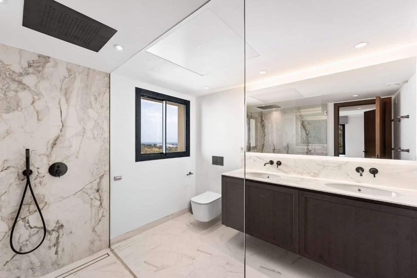 Modern loft-style apartment bathroom with marble accents and scenic views in Nueva Andalucia.
