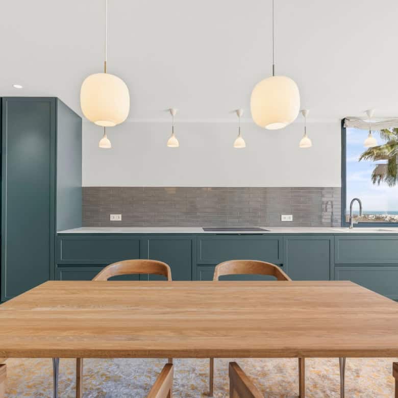 Blue kitchen with sleek cabinets and a large window overlooking the sea in Palacetes Les Belvederes.