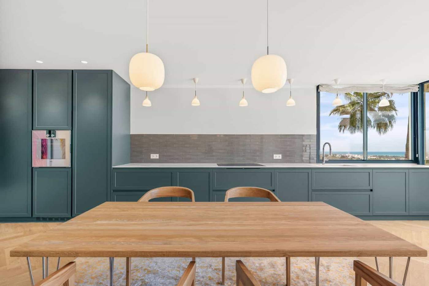 Blue kitchen with sleek cabinets and a large window overlooking the sea in Palacetes Les Belvederes.