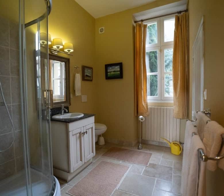 Charming bathroom in a beautiful French home with a shower, sink, and window view. Perfect for comfo.