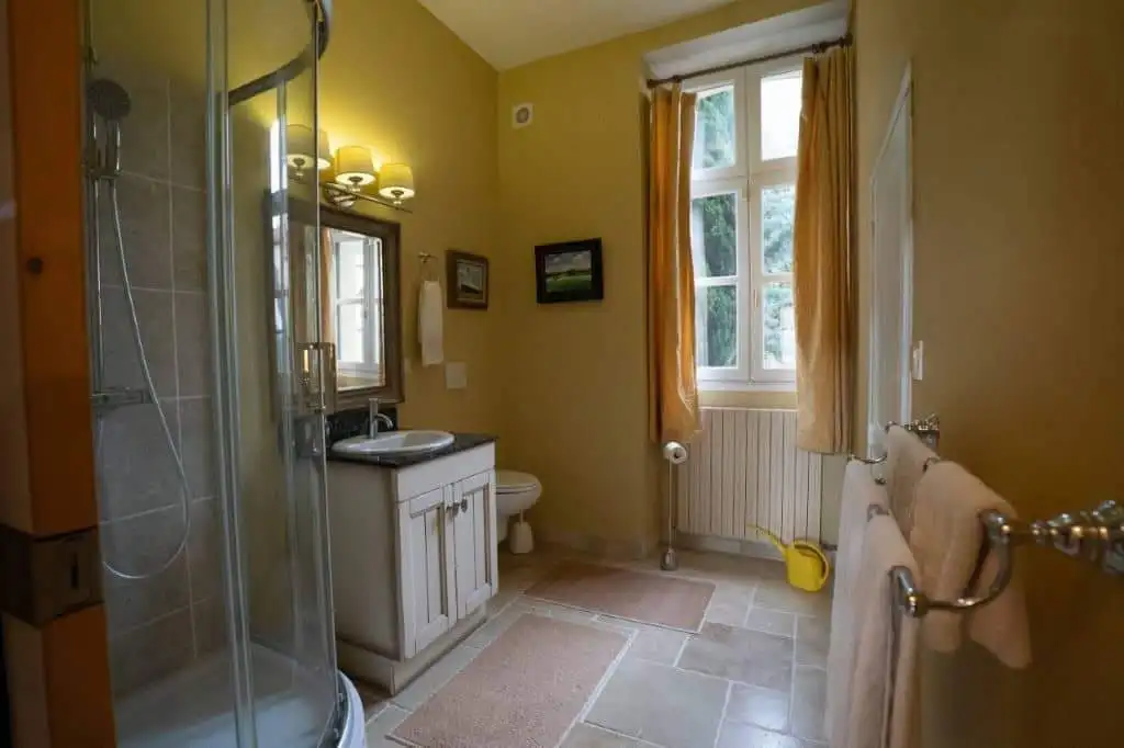 Charming bathroom in a beautiful French home with a shower, sink, and window view. Perfect for comfo.