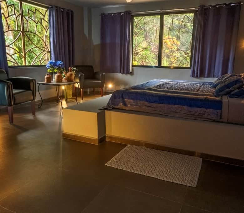 Spacious bedroom featuring large windows overlooking a flowing river in Llurimagua, Ecuador. Perfect.