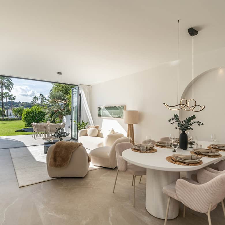 Spacious living area in Marbella Golf Valley townhouse with stylish decor and large glass doors open.