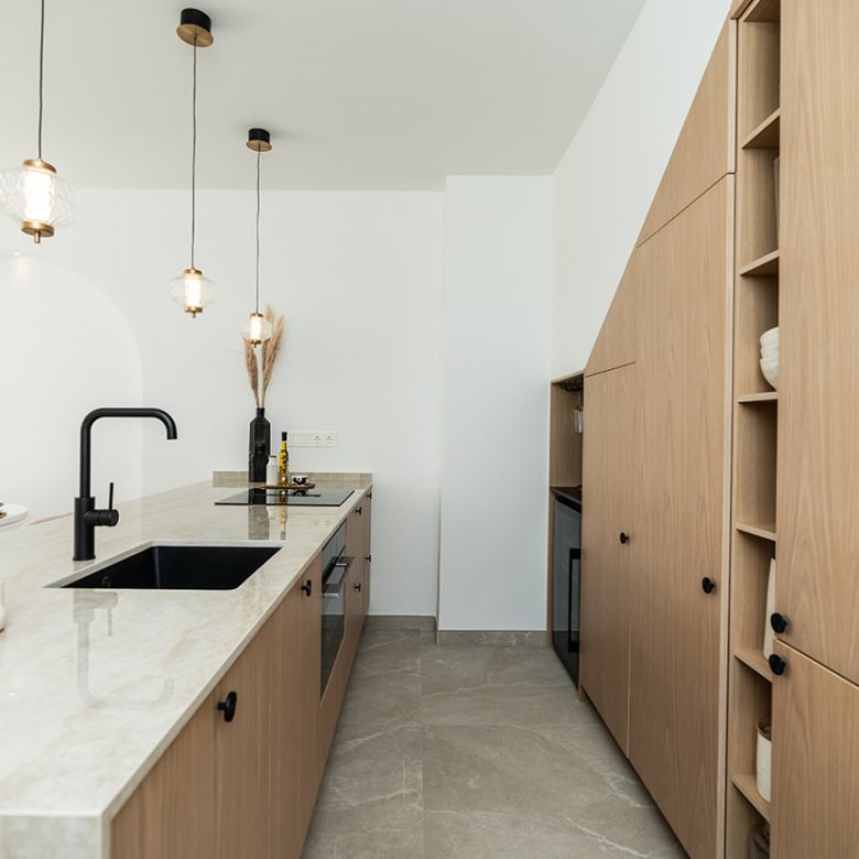 Contemporary kitchen featuring wooden cabinetry, a sleek black sink, and stylish pendant lights, per.