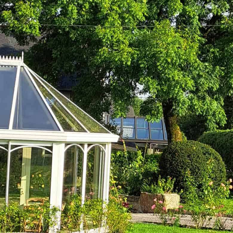 Elegant estate with lush greenery and a glass conservatory in Brittany.