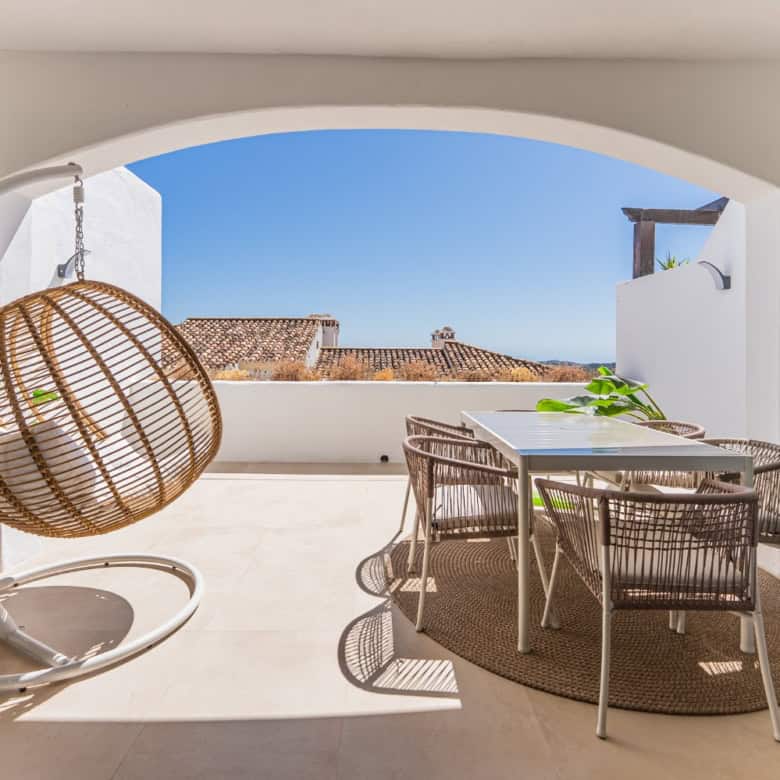 Balcony with sea view, outdoor dining, and hanging chair in Los Arqueros Benahavis.