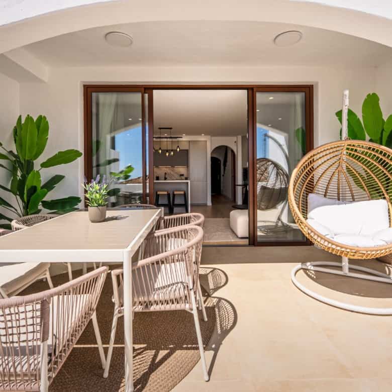 Outdoor terrace featuring dining table and stylish lounge chair with lush greenery.