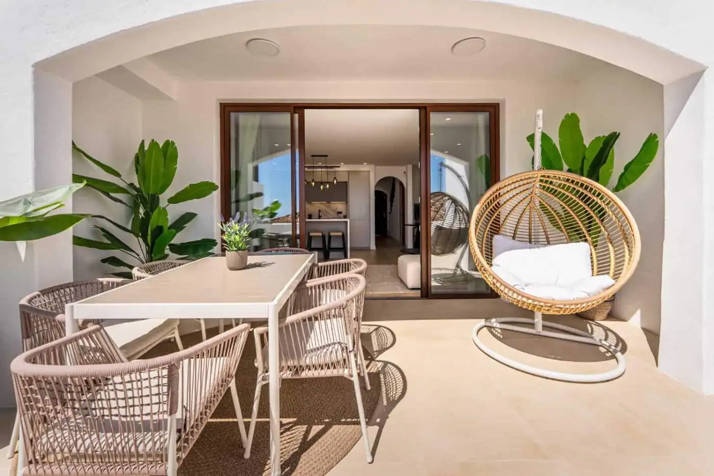 Outdoor terrace featuring dining table and stylish lounge chair with lush greenery.