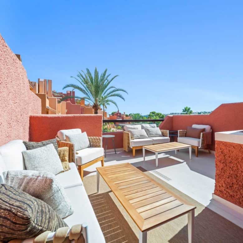 Spacious outdoor terrace of a luxury townhouse in El Palmeral, Nueva Andalucía with seating and scen.