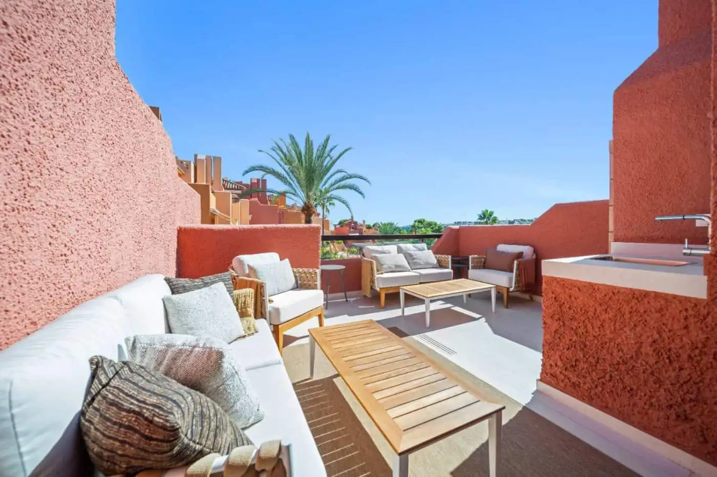 Spacious outdoor terrace of a luxury townhouse in El Palmeral, Nueva Andalucía with seating and scen.