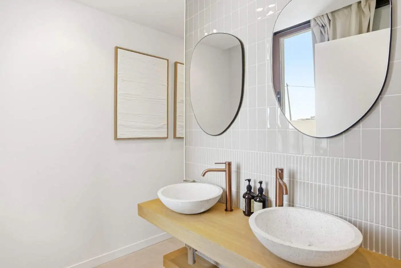 Bathroom with dual vessel sinks, round mirrors, and minimalist decor.