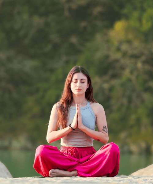 Meditation woman sitting cross-legged in a peaceful outdoor setting.