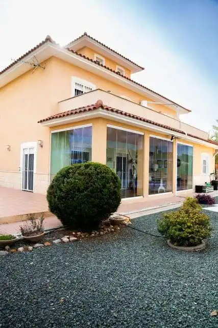 Modern 4-bedroom villa with large glass windows and landscaped garden in Totana Murcia.
