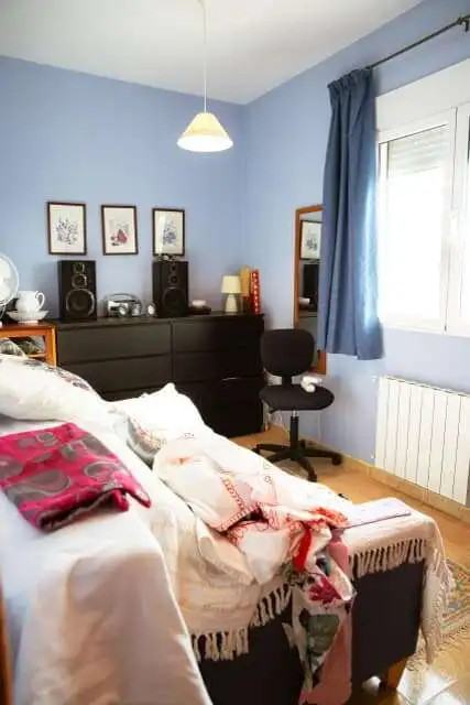 Bright bedroom featuring blue walls, a large window with blue curtains, and contemporary furniture.