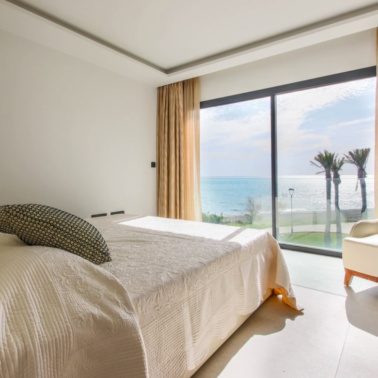 Modern beachfront townhouse bedroom overlooking the sea and palm trees in Estepona West.