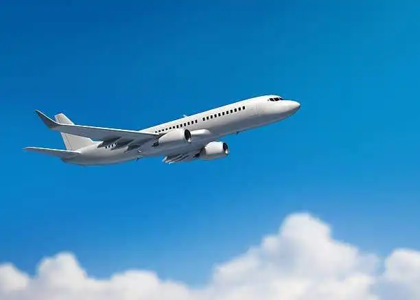 Private jet soaring through blue sky with clouds.