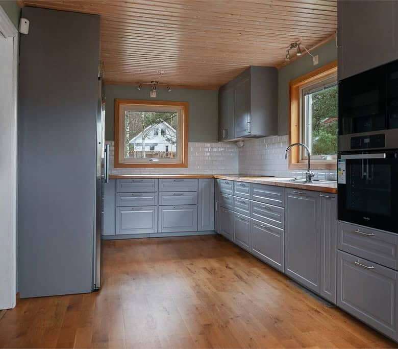 Spacious kitchen featuring wooden floors, ample cabinetry, and large windows offering natural light.