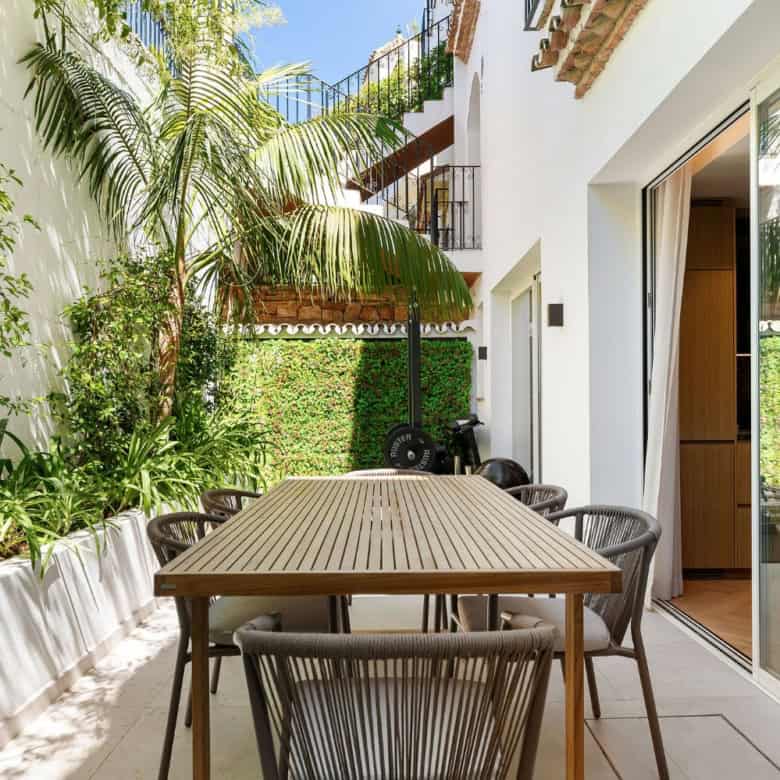 Modern Marbella townhouse terrace with outdoor dining area and lush greenery.