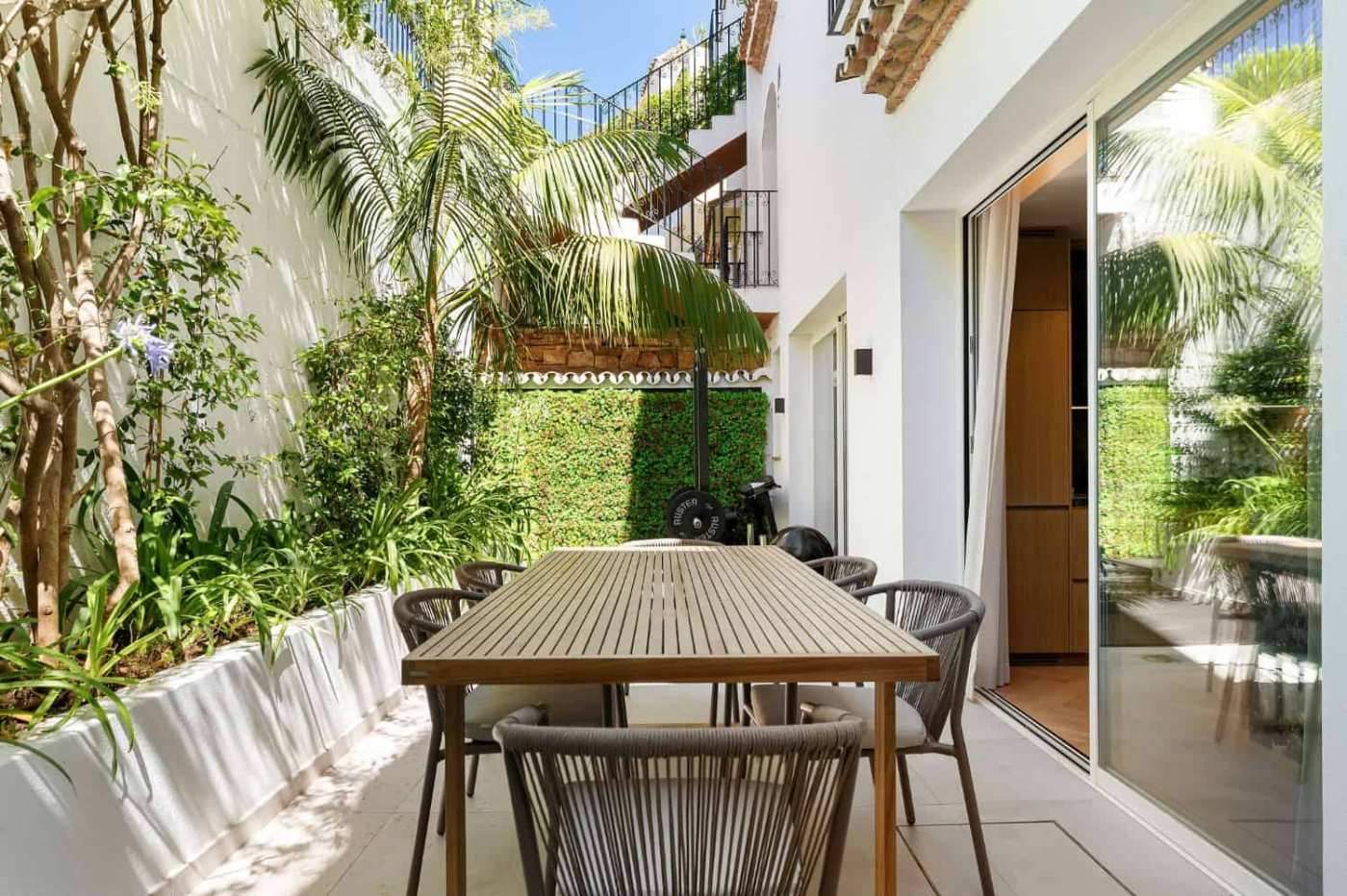 Modern Marbella townhouse terrace with outdoor dining area and lush greenery. Modern Marbella townhouse terrace with outdoor dining area and lush greenery.