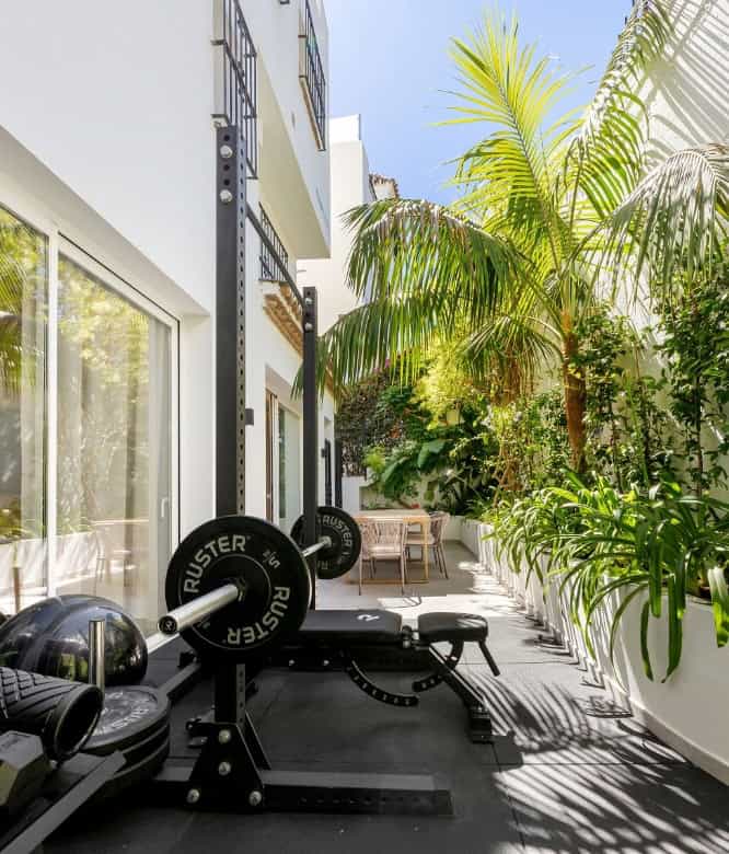 Outdoor gym area with fitness equipment and lush greenery in Marbella.