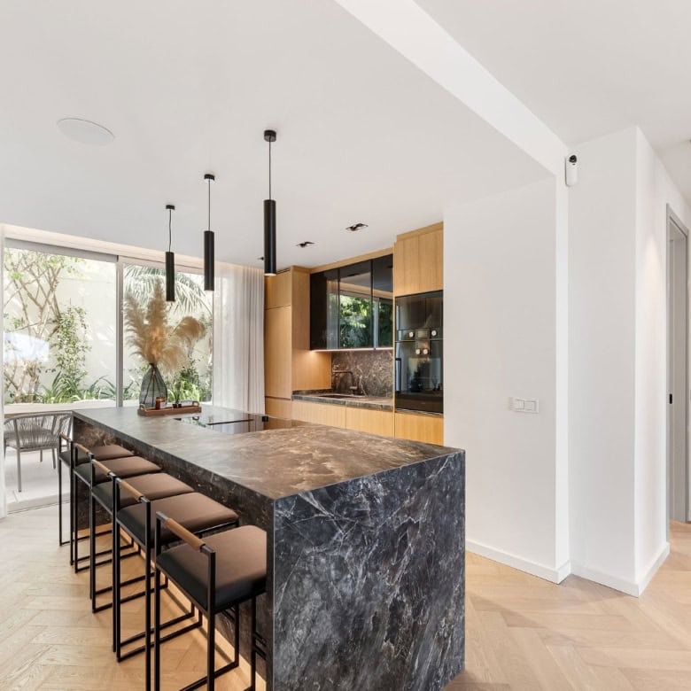 Modern kitchen with marble island in Marbella townhouse.