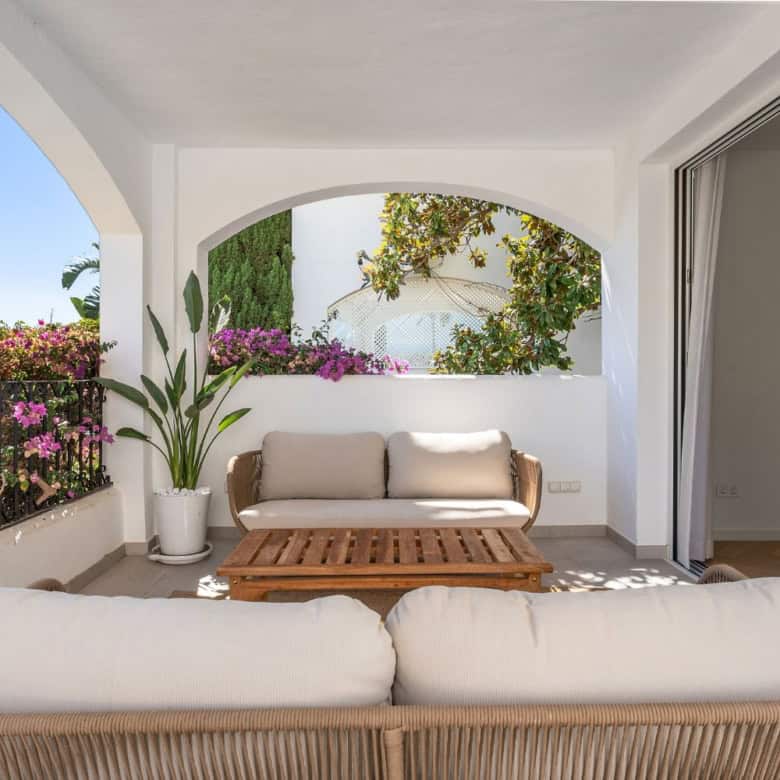 Balcony of a luxury townhouse in Club Sierra, Marbella, showcasing outdoor seating and vibrant garde.