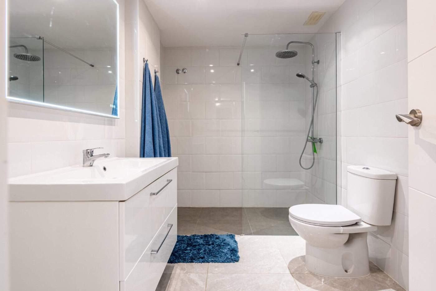 Modern bathroom with walk-in shower, white sink, and toilet in a contemporary setting.
