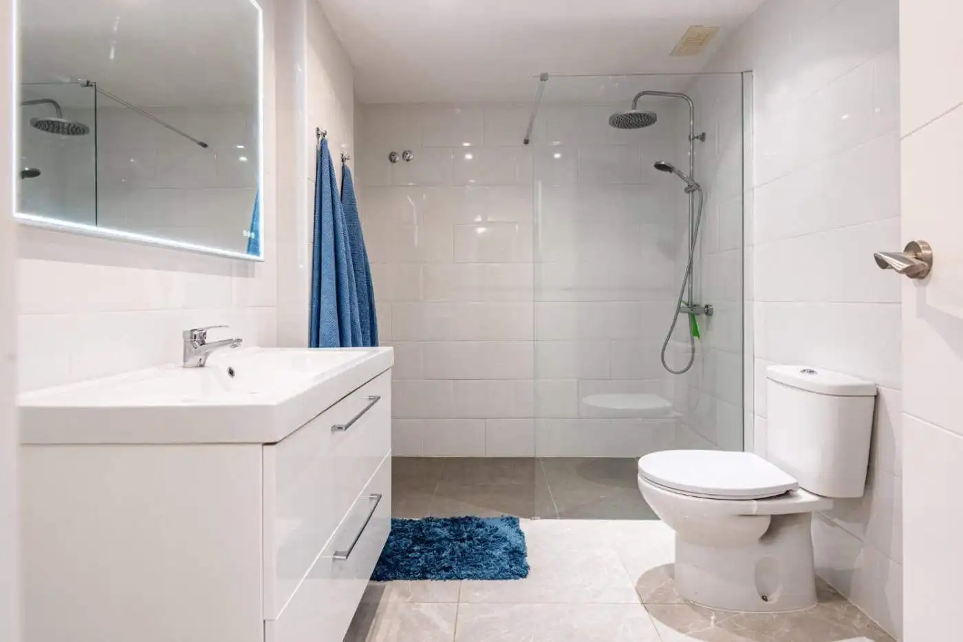 Modern bathroom with walk-in shower, white sink, and toilet in a contemporary setting.