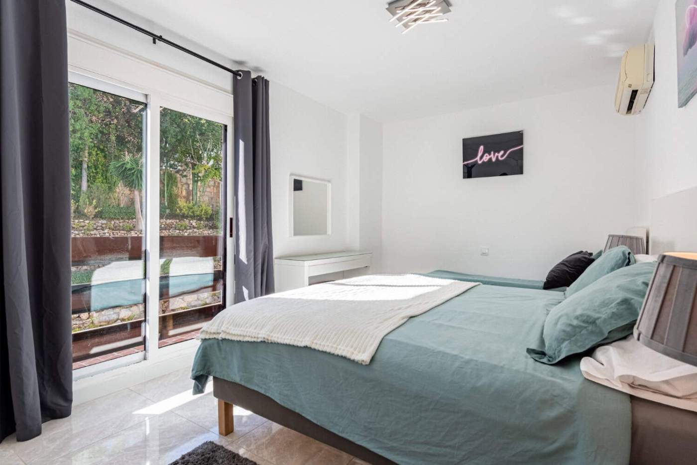 Spacious bedroom featuring large glass doors opening to a balcony, bright and airy interior.