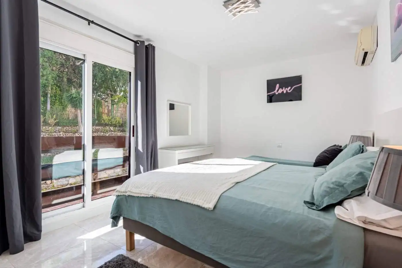 Spacious bedroom featuring large glass doors opening to a balcony, bright and airy interior.