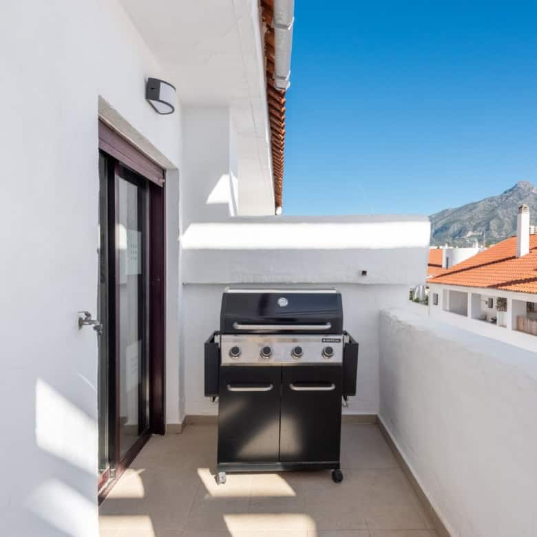 Balcony with a barbecue grill overlooking the rooftops and mountains in La Maestranza, Nueva Andaluc.