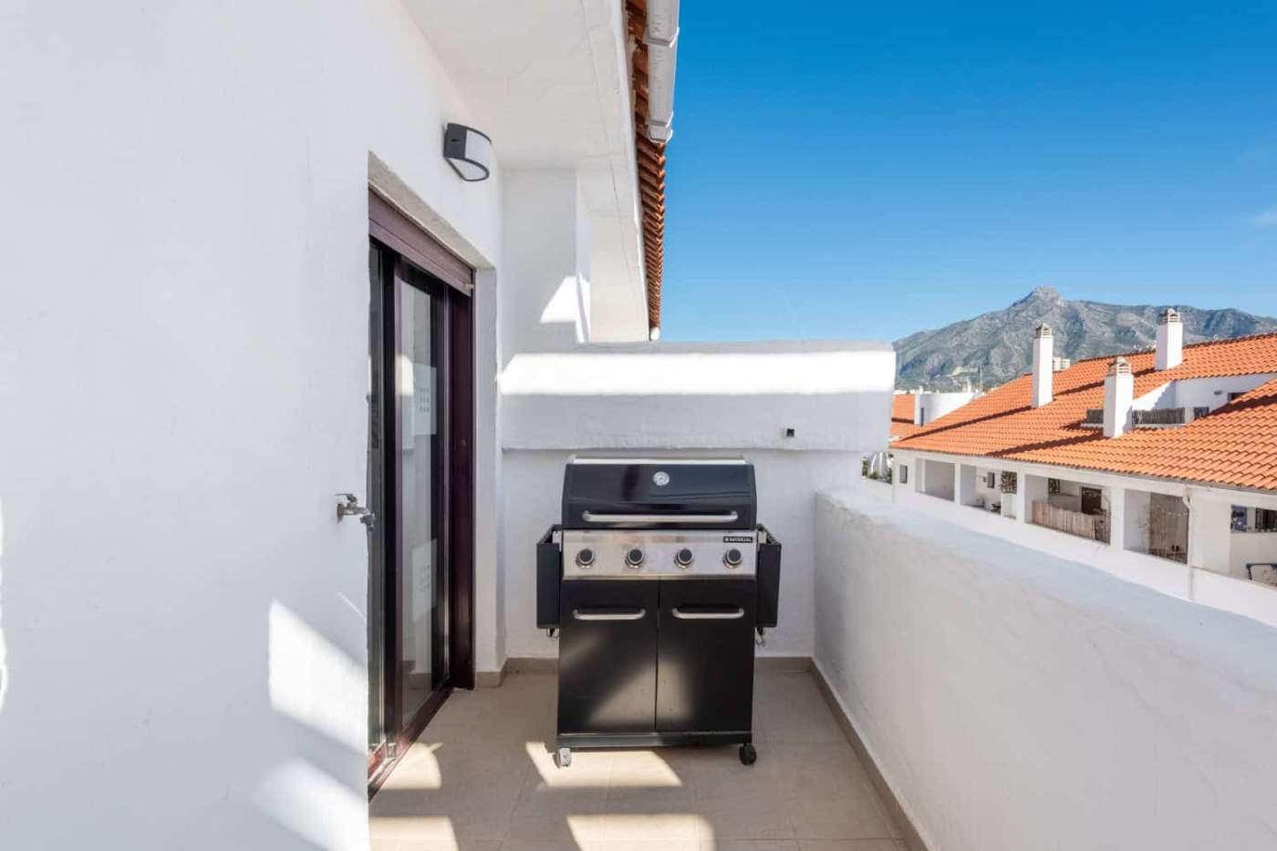 Balcony with a barbecue grill overlooking the rooftops and mountains in La Maestranza, Nueva Andaluc.