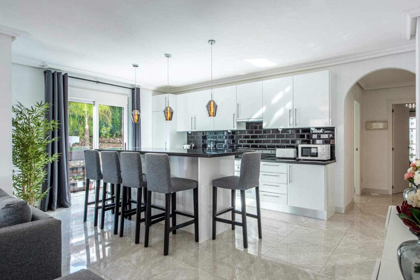 Spacious modern kitchen in La Maestranza with sleek white cabinets and black backsplash.