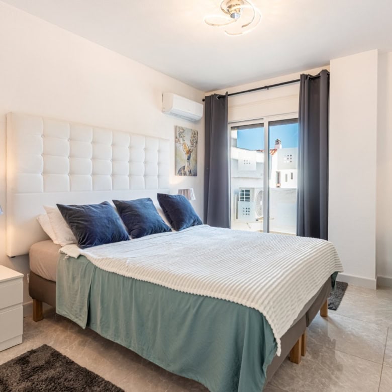 Spacious corner bedroom with contemporary decor, large window, and stylish furnishings in La Maestra.