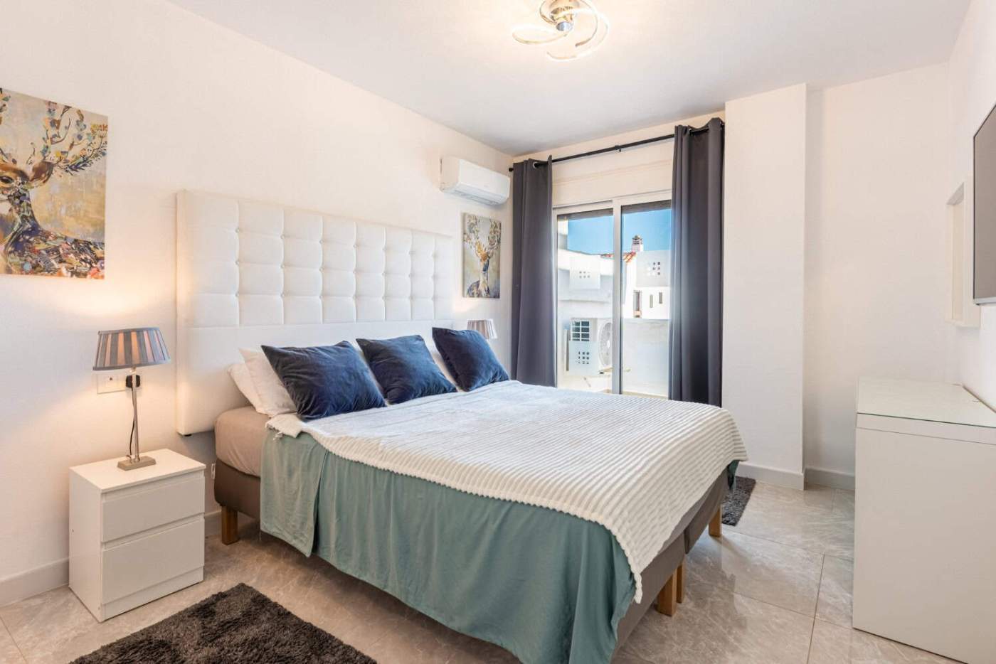 Spacious corner bedroom with contemporary decor, large window, and stylish furnishings in La Maestra.