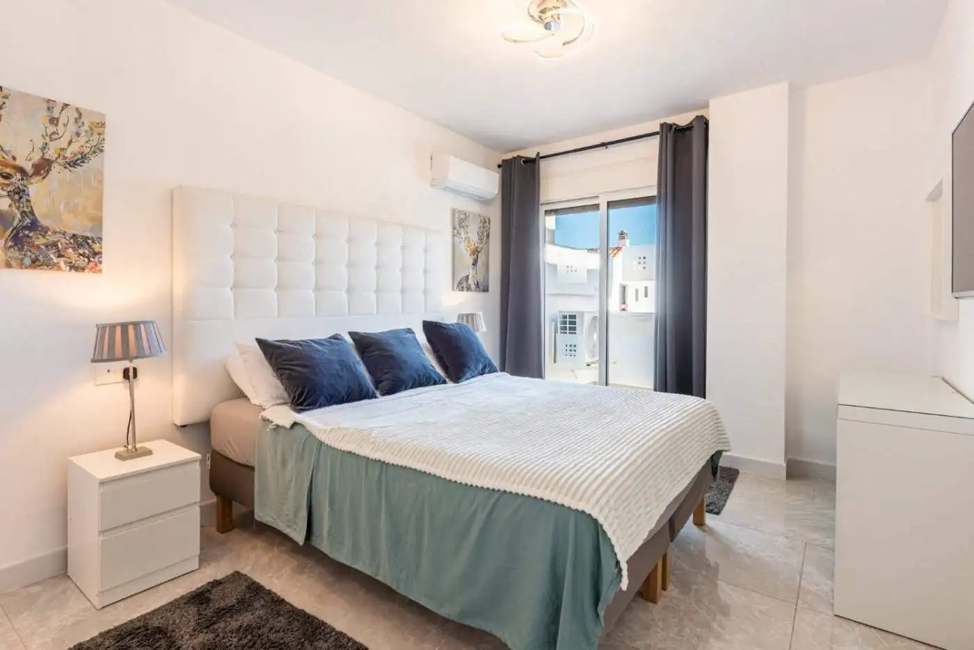 Spacious corner bedroom with contemporary decor, large window, and stylish furnishings in La Maestra.