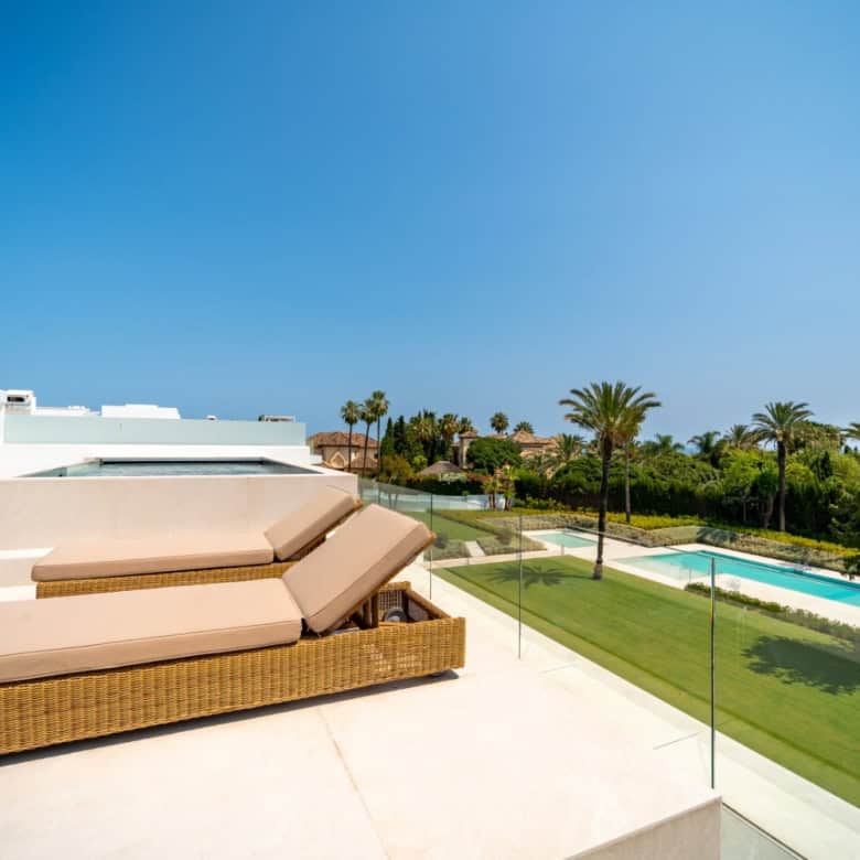 Luxury villa rooftop lounge with sunbeds, pool, and scenic views of the surrounding landscape.