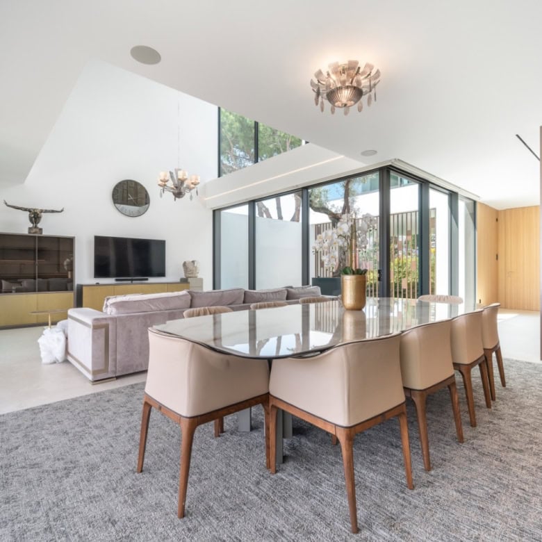 Modern villa interior with spacious dining and living area, large windows, and stylish decor.