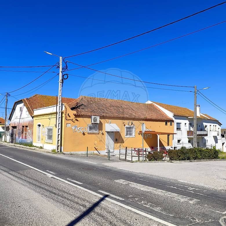 Land plot for sale in Cabanas Setubal Portugal with nearby houses and clear blue sky.