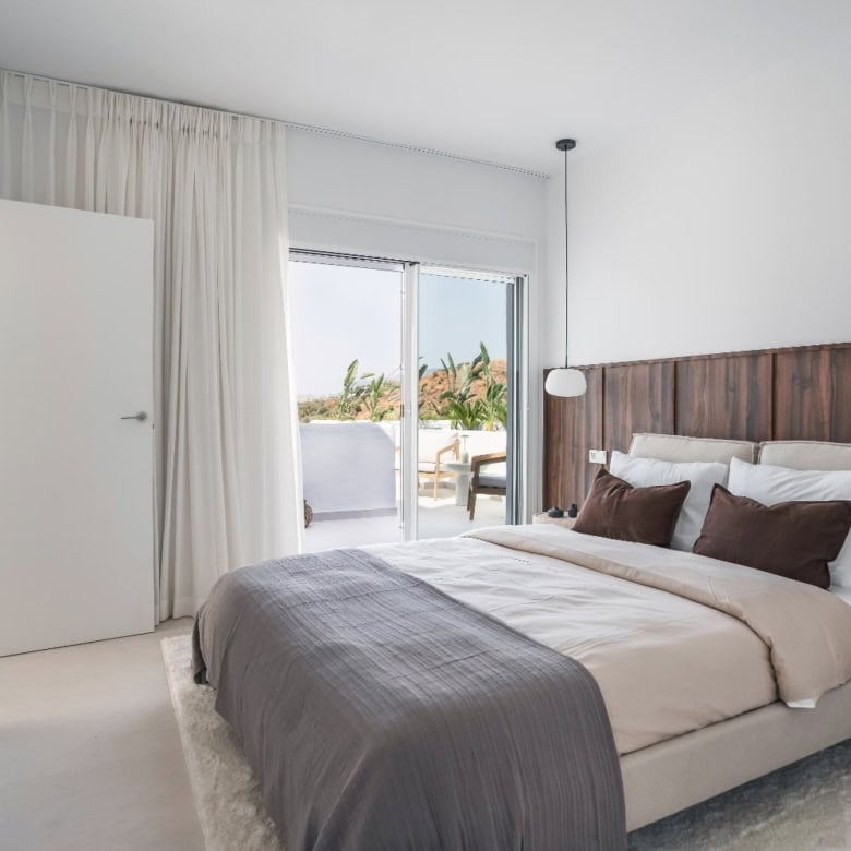 Spacious bedroom featuring a balcony with sea views, white walls, and contemporary decor.