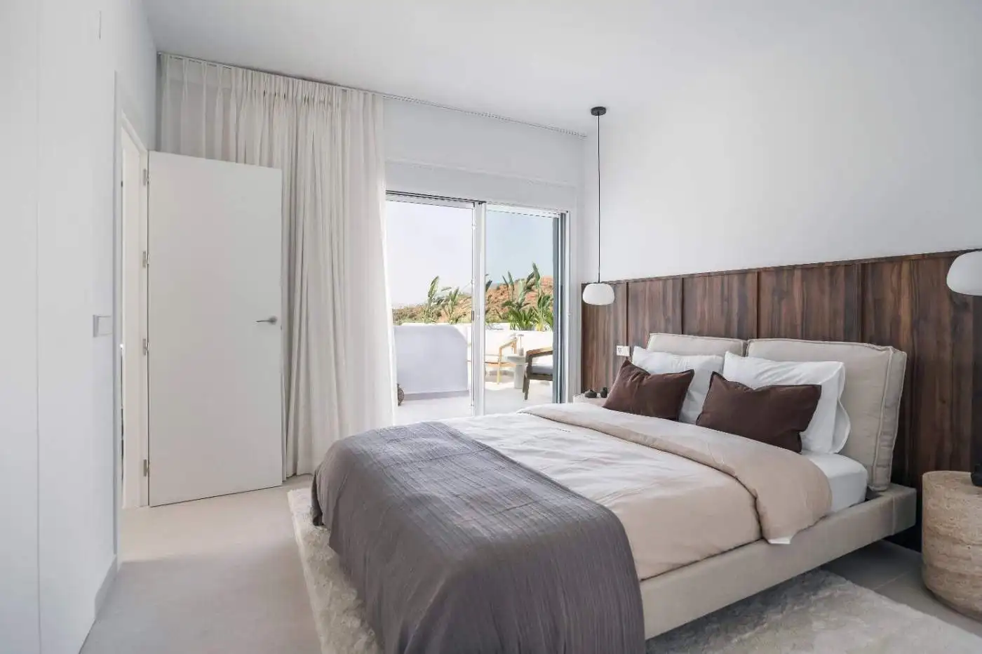Spacious bedroom featuring a balcony with sea views, white walls, and contemporary decor.