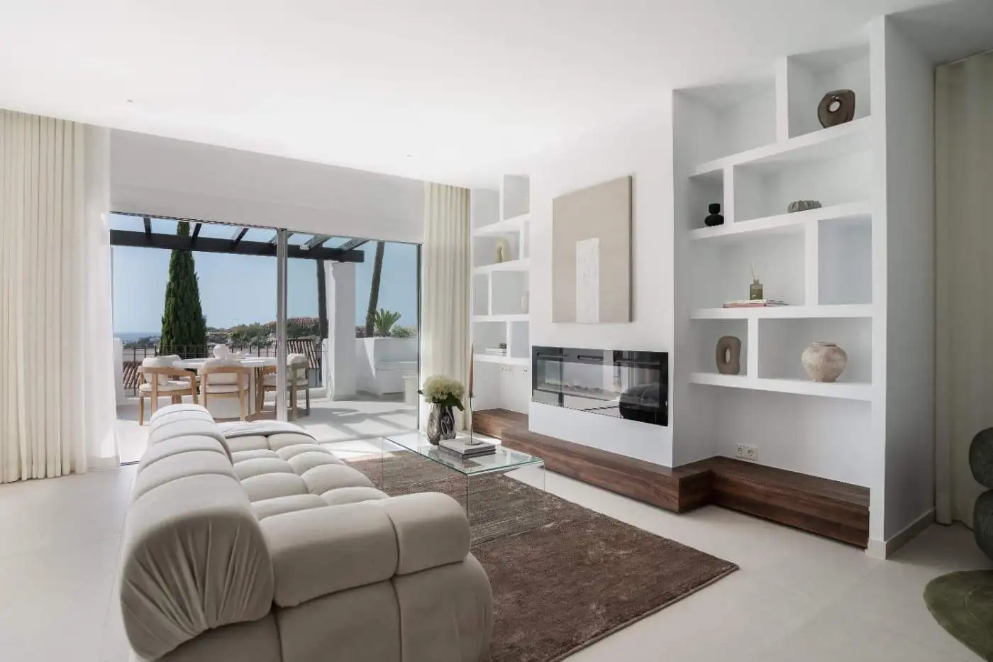 Elegant living room with modern decor and large windows overlooking outdoor terrace.