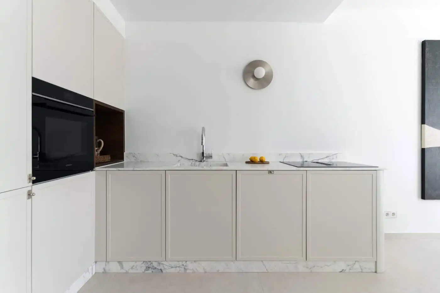 Modern minimalist kitchen with white cabinets and marble countertops.