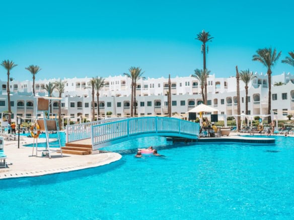 Beautiful resort pool with palm trees and white buildings in Egypt, perfect for relaxation.