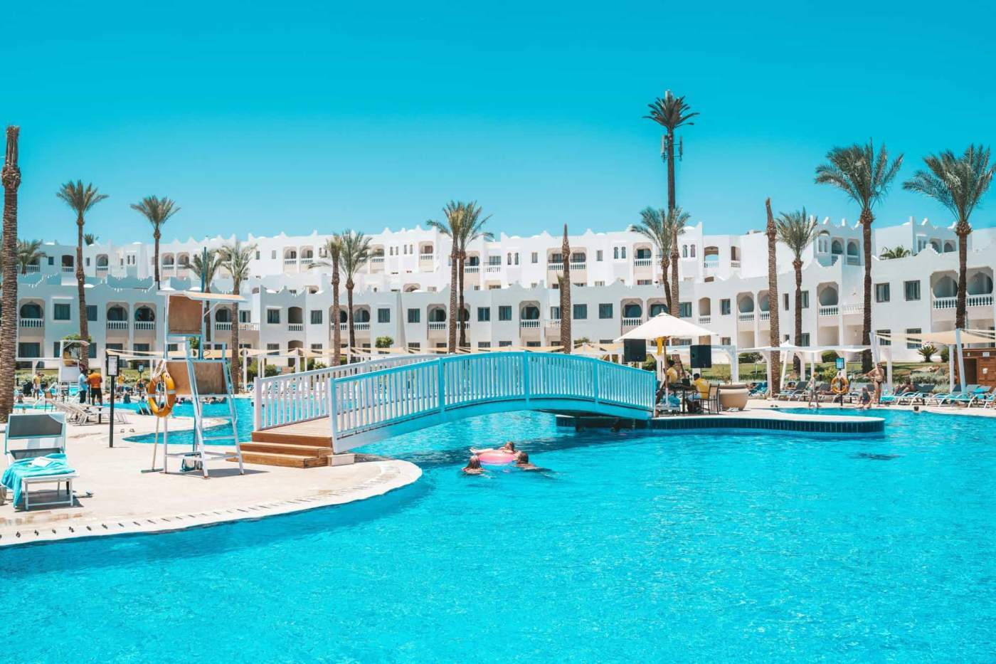 Beautiful resort pool with palm trees and white buildings in Egypt, perfect for relaxation.