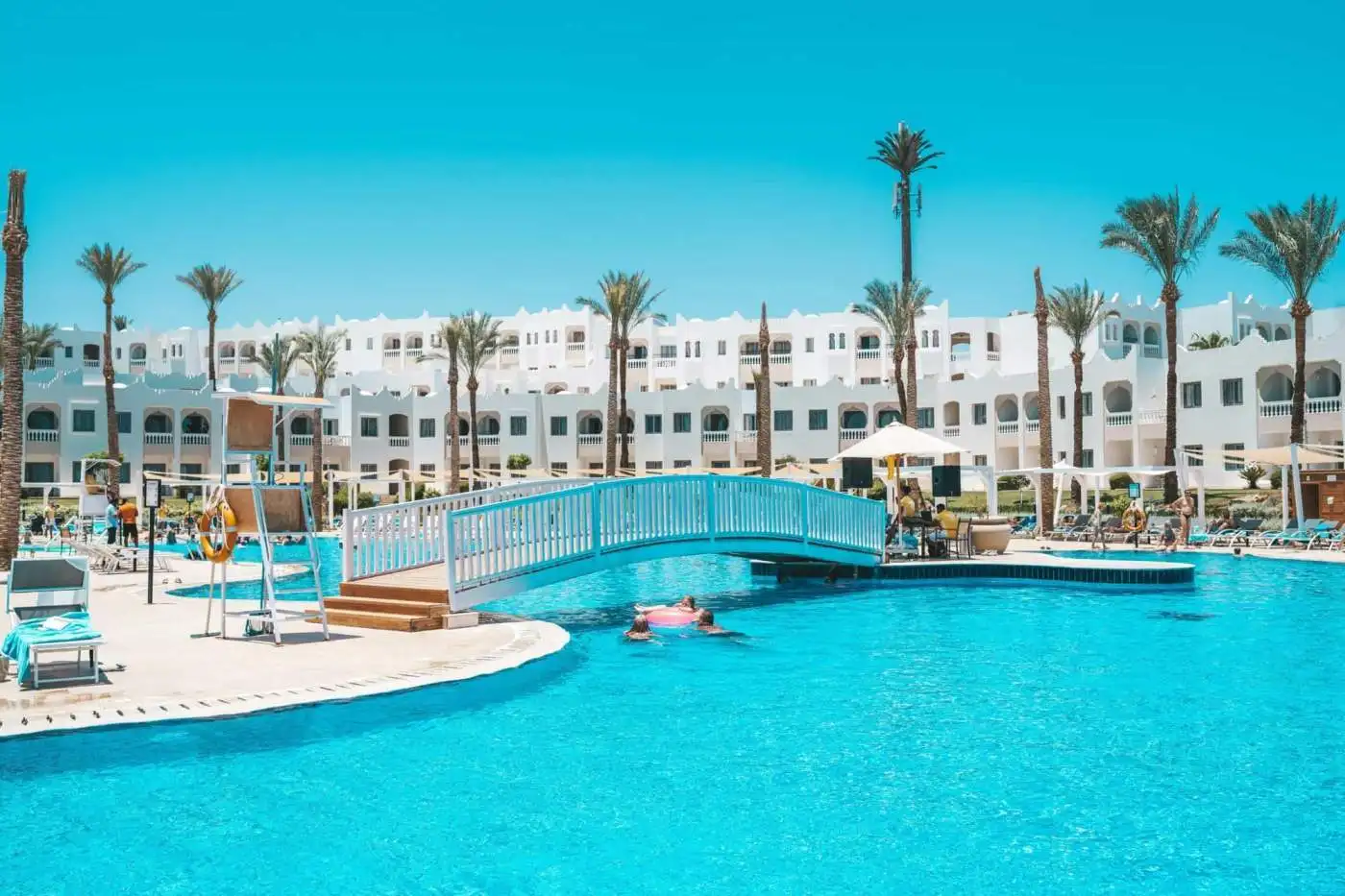 Beautiful resort pool with palm trees and white buildings in Egypt, perfect for relaxation.